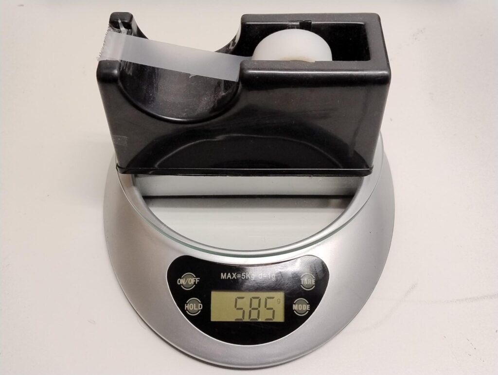 A sticky tape dispenser on top of kitchen scales, the display shows 585 grams.